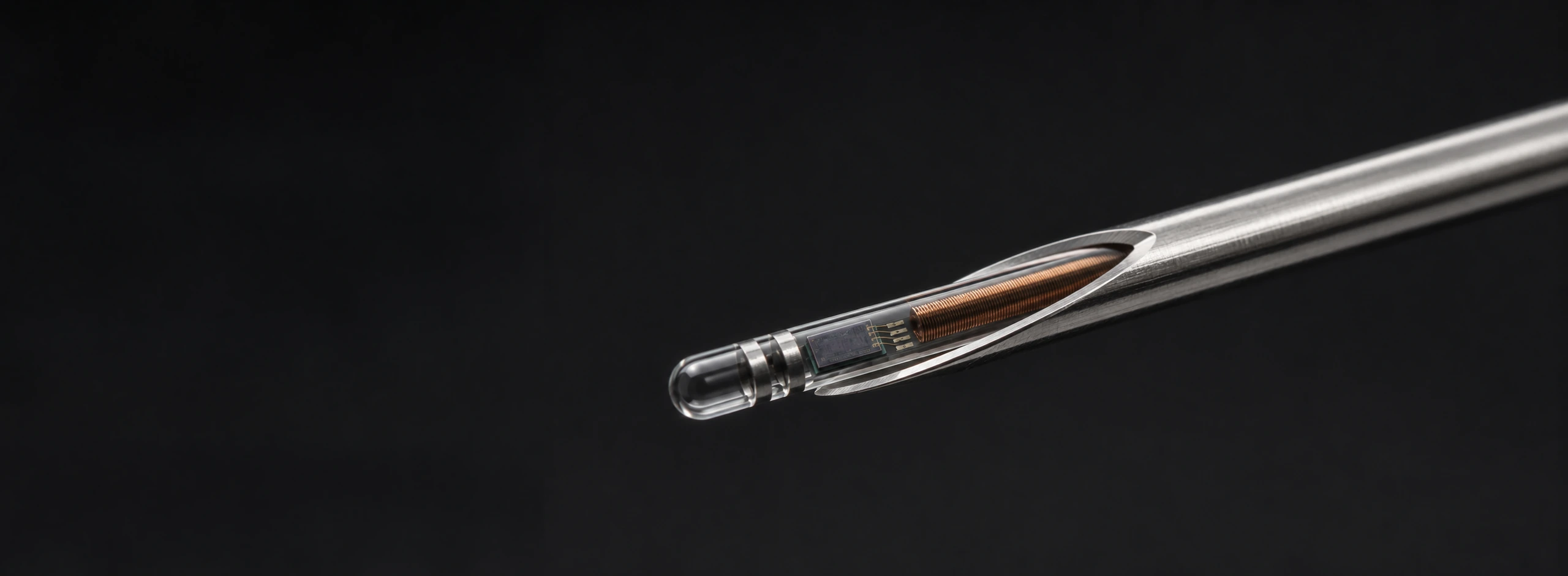 BERO NanoChip concept - a sealed glass capsule holding a copper coil and a small silicon die, shown inside the bevel of a standard microchip injection needle.